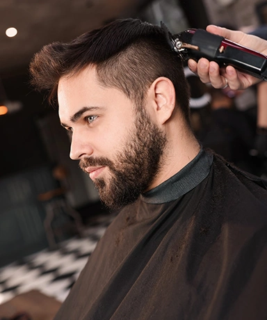Professional hairdresser working with client in barbershop