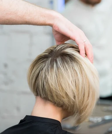 Closeup back view of teen young girl woman sitting in chair in hair salon