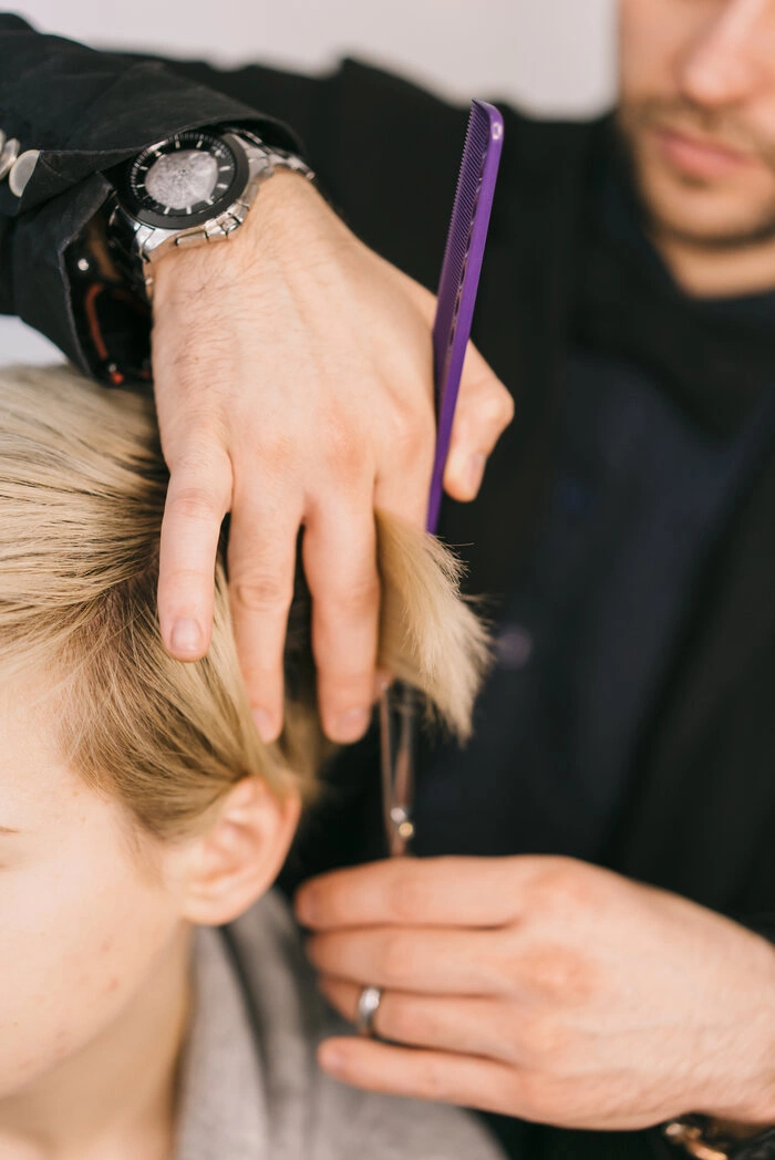 Man working as hairdresser and cutting hair of female customer