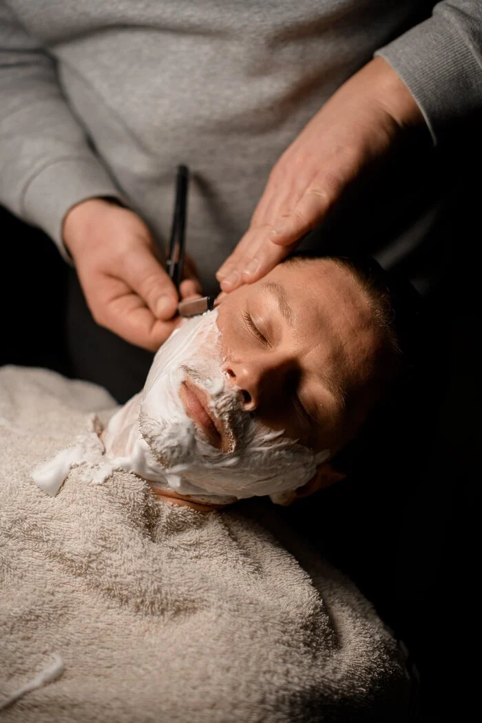 Barber shaving client with vintage straight razor